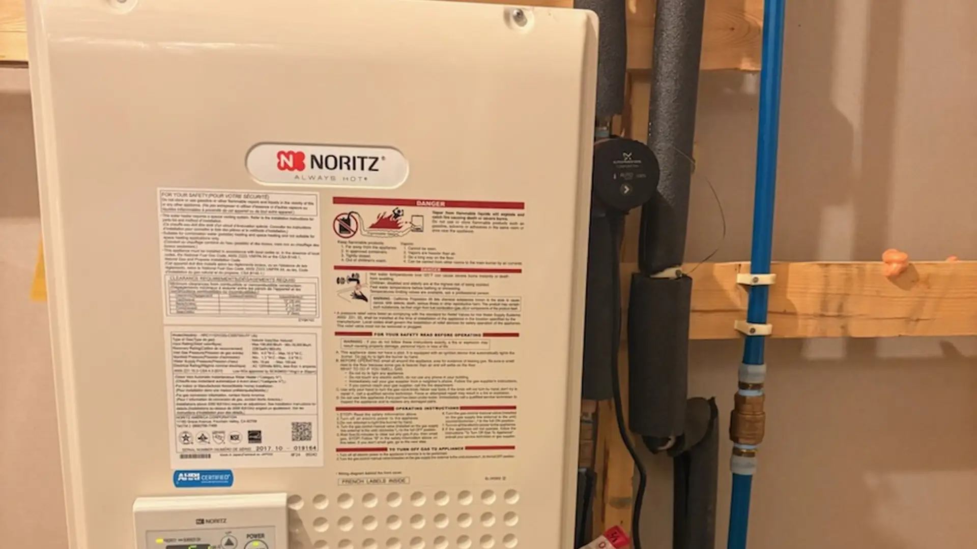 Wall-mounted Noritz tankless water heater with gas and water connections