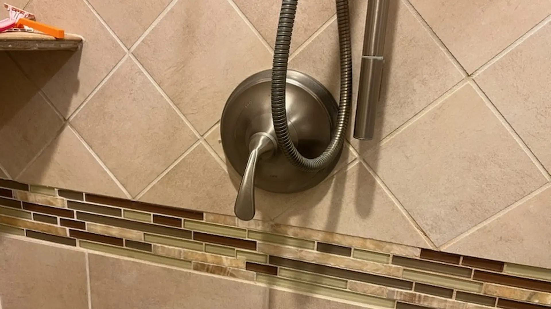 New brushed-nickel shower valve trim and handheld shower on tile