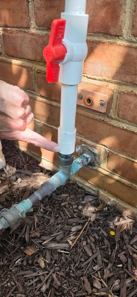 Irrigation supply line with shutoff valve at a brick wall