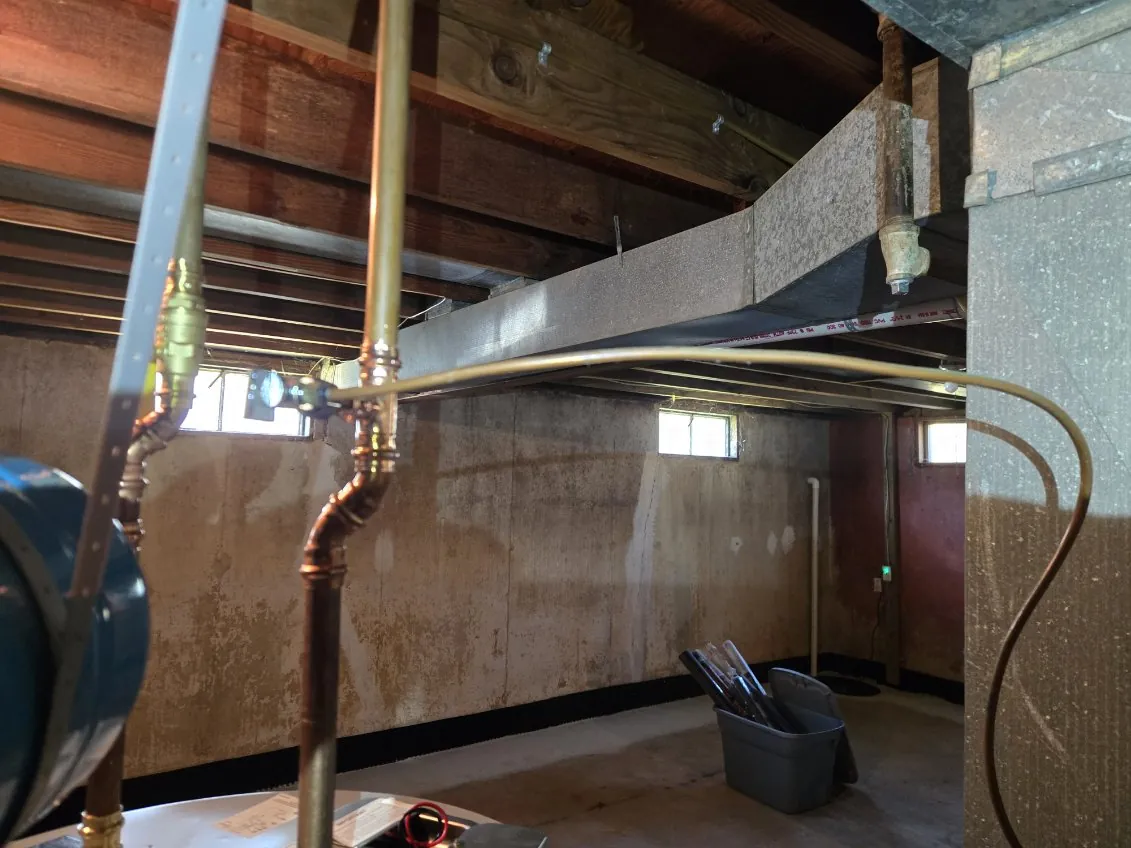 New copper water lines rising from the water heater toward the basement ceiling
