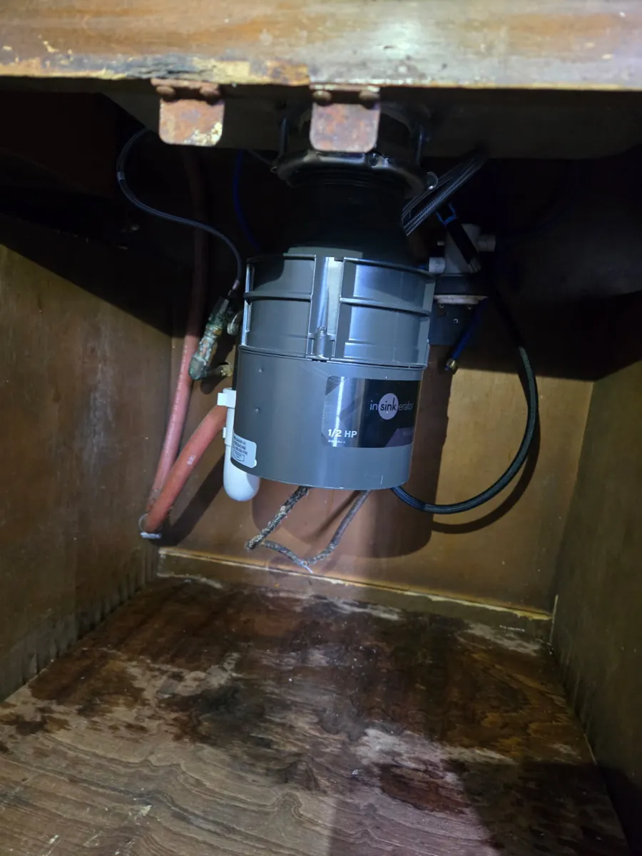 New gray InSinkErator 1/2 HP garbage disposal mounted under a kitchen sink inside a wood cabinet
