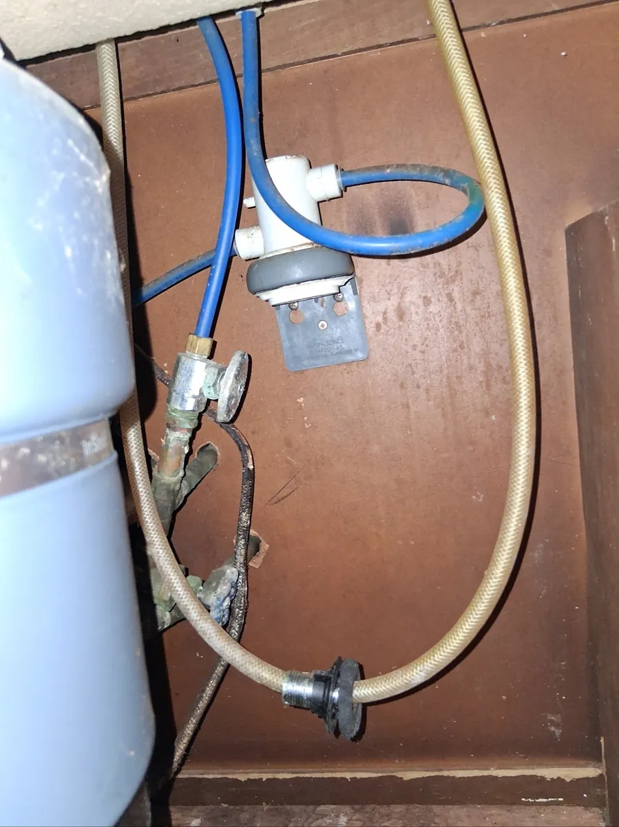 Old corroded shutoff valves and supply lines under a kitchen sink