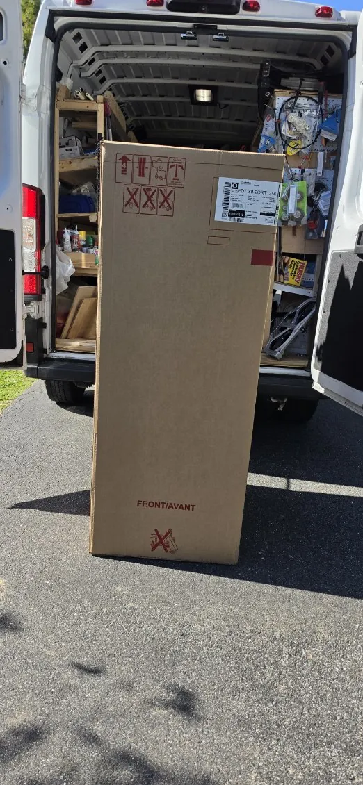 Boxed 80-gallon water heater standing in front of an open work van