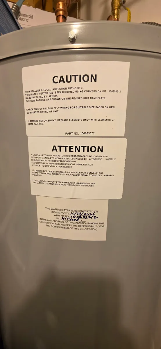 Caution and conversion labels on the new water heater noting it was modified with a conversion kit