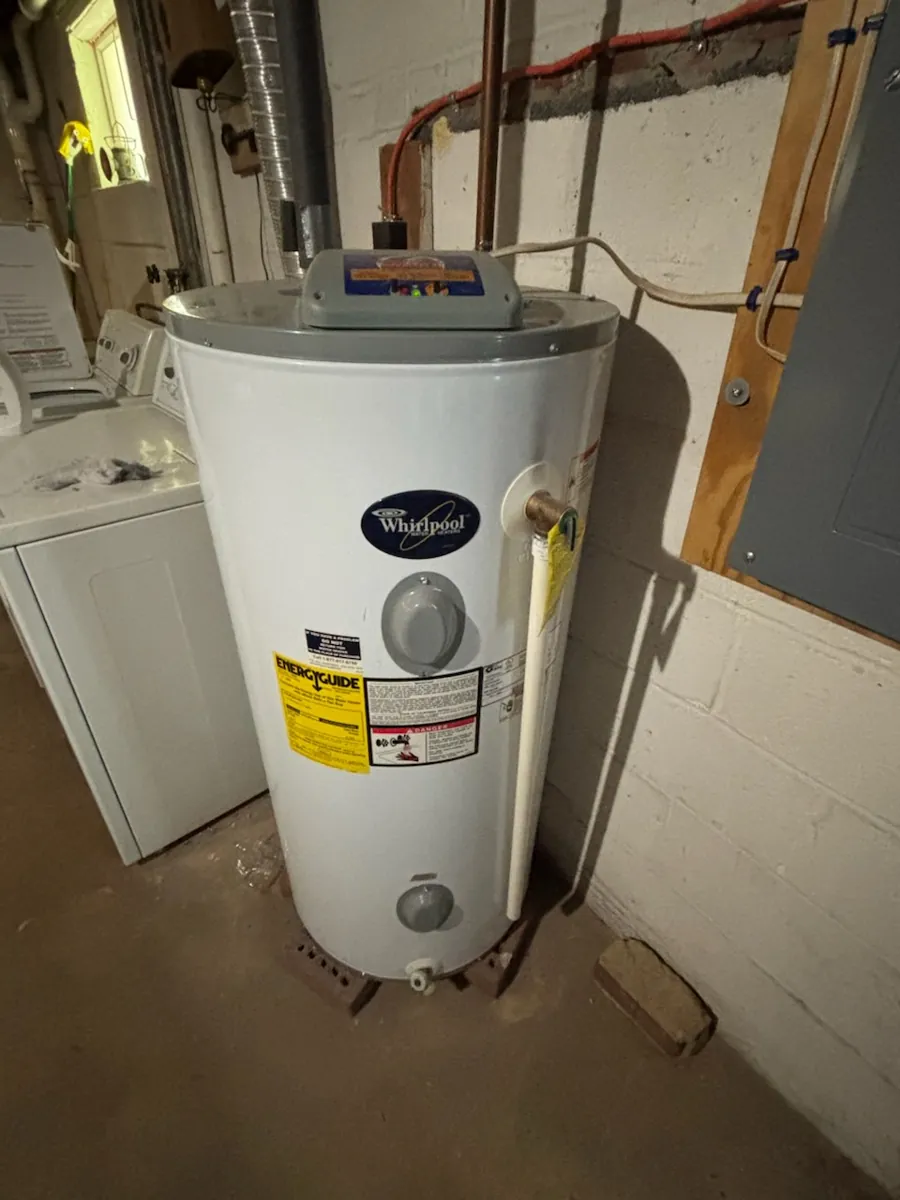 Whirlpool 50-gallon electric water heater in an unfinished basement next to a washer