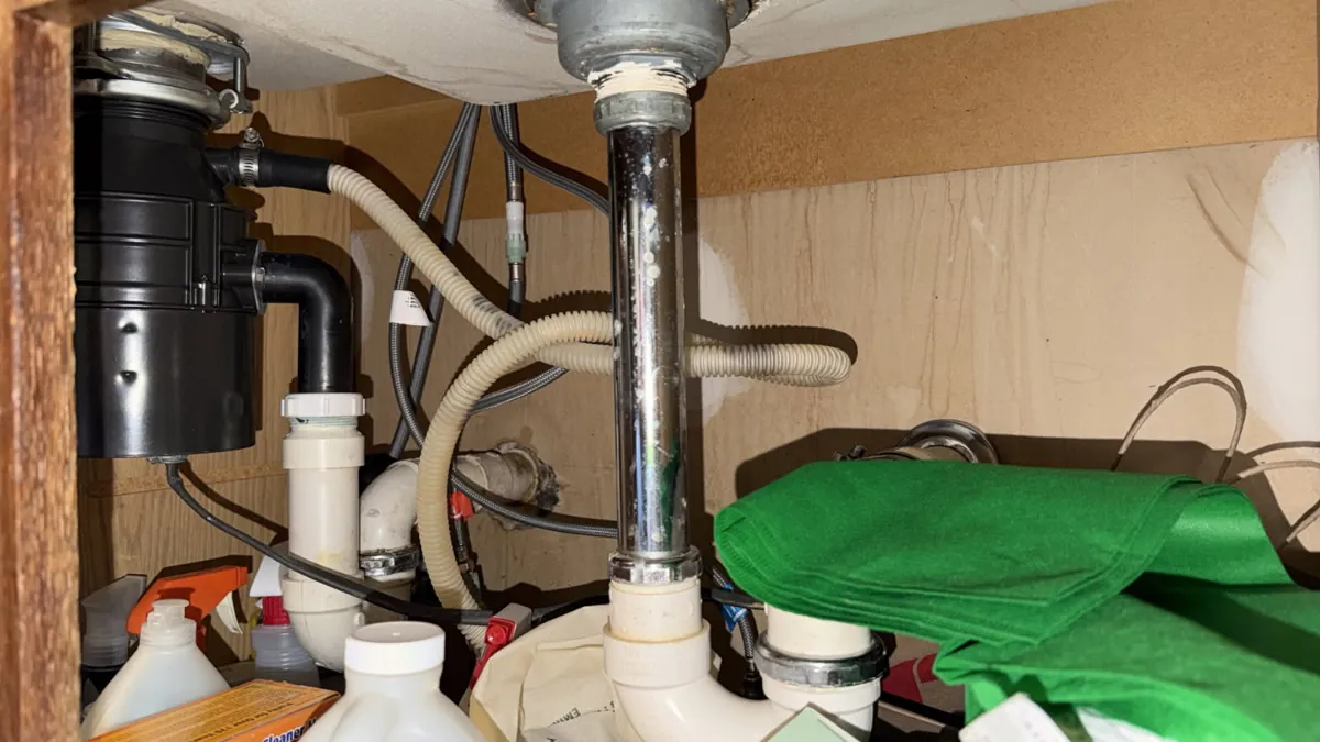 Close view of the under-sink drain layout with the disposal outlet elbow and the trap