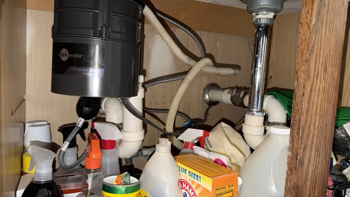 Another angle of the garbage disposal and drain pipes under the kitchen sink